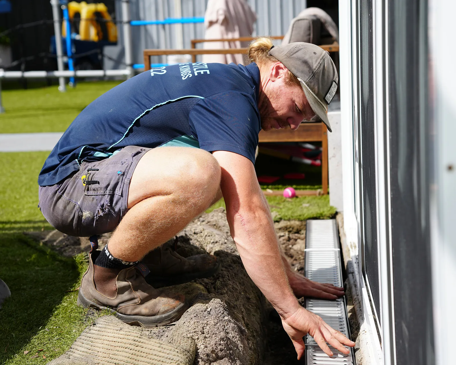 Plumber installing a strip drain beside a sliding door